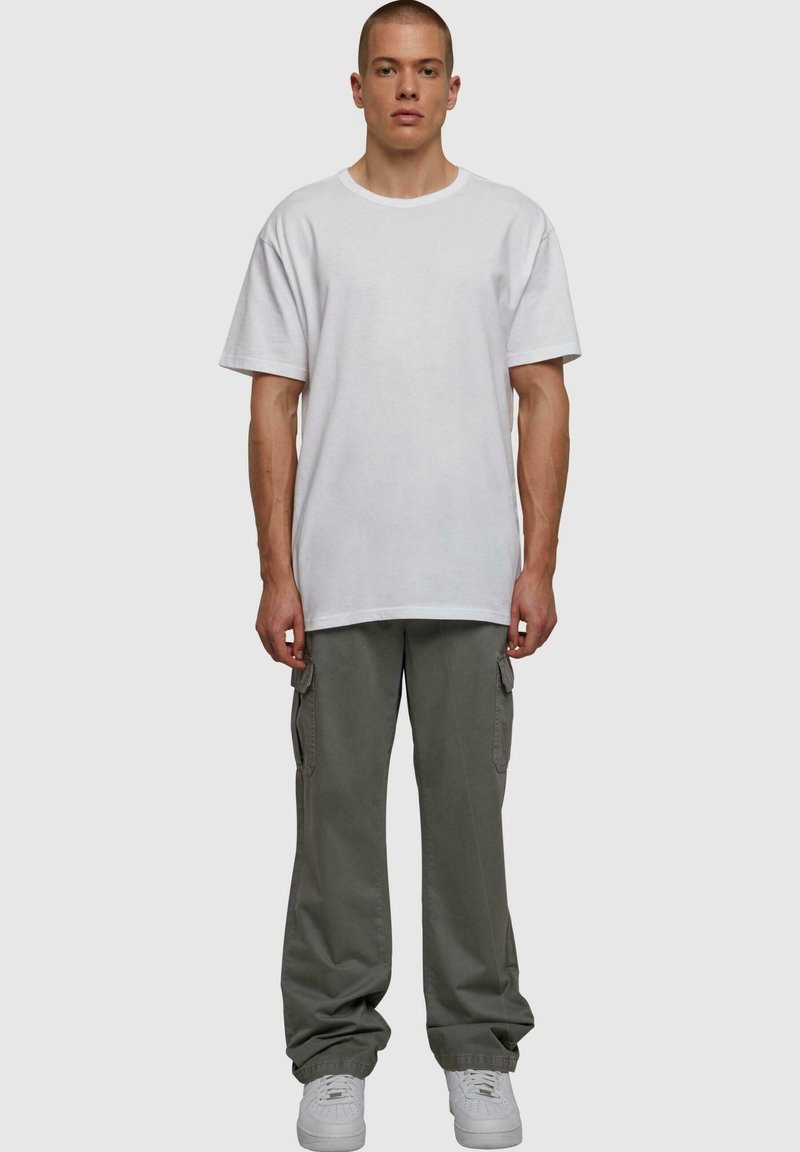 Witte katoenen t-shirt, relaxed fit, gecombineerd met grijze cargo broek met zijzakken en een losse pasvorm, afgewerkt met witte sneakers.