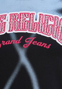 Black cotton T-shirt featuring bold red and pink lettering with rhinestone accents. Light blue graphics blend into the fabric texture.