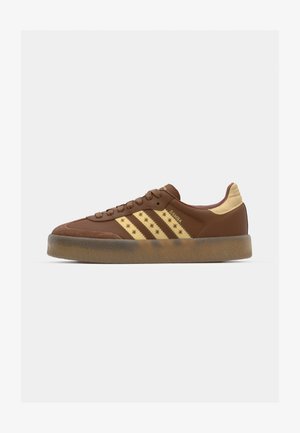 Sneaker in suede marrone con tre strisce dorate, dettagli in beige texturizzato, suola in gomma e motivo a stella lungo il lato.