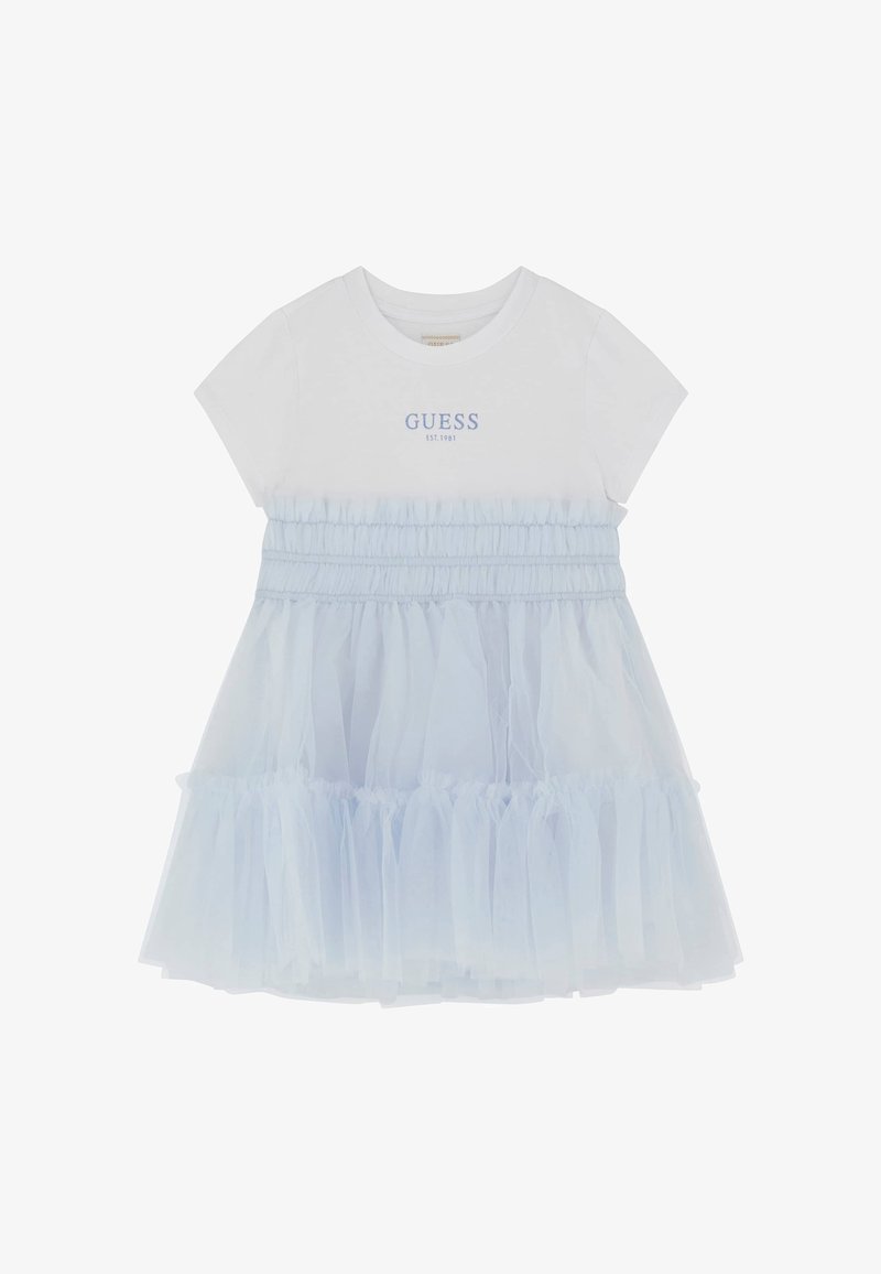White t-shirt dress with light blue tulle skirt, smocked waist, and "GUESS EST. 1981" logo in blue. Short sleeves and layered texture.