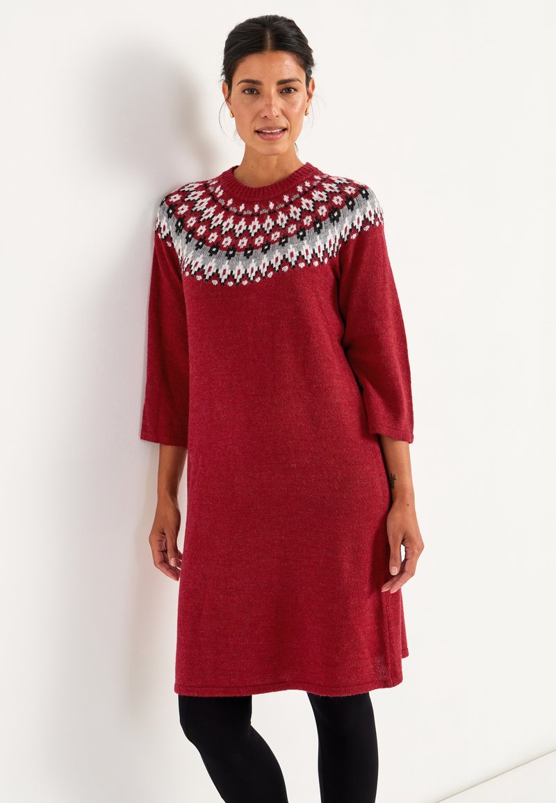 Rotes Strickkleid mit rundem Ausschnitt, das eine gemusterte Passe in Weiß, Schwarz und Rot aufweist. Es hat Dreiviertelärmel und eine lockere Passform.