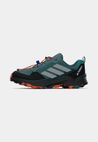 Sapatilha de trilha Adidas Terrex em teal e preto com atacadores laranja e sola com padrão preto-laranja, vista de lado sobre um fundo branco.
