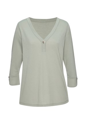 Hellgrünes Damenoberteil mit V-Ausschnitt, langen Ärmeln und Knopfdetail am Ausschnitt und den Manschetten vor schlichten weißem Hintergrund.