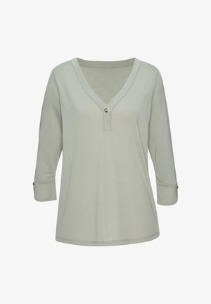 Hellgrünes Damenoberteil mit V-Ausschnitt, langen Ärmeln und Knopfdetail am Ausschnitt und den Manschetten vor schlichten weißem Hintergrund.