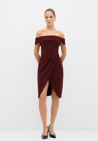 Burgundin off-the-shoulder mekko, jossa on tiukka yläosa, kääntömuotoilu, epäsymmetrinen helma ja rekeä korkealle lahkeelle ulottuva halkio, valmistettu teksturoidusta kankaasta.