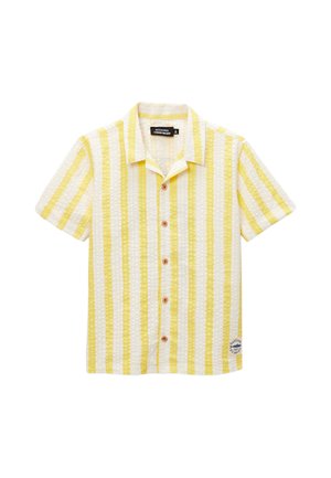 Chemise à manches courtes avec rayures verticales jaunes et blanches et une petite pièce près de l'ourlet inférieur sur fond blanc.