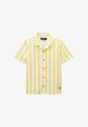 Chemise à manches courtes avec rayures verticales jaunes et blanches et une petite pièce près de l'ourlet inférieur sur fond blanc.