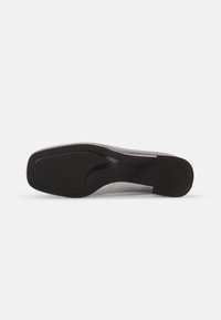 Suola di scarpa nera con una finitura liscia, caratterizzata da una forma leggermente curva e gomma testurizzata per una migliore aderenza. Include una sezione di tacco sottile.