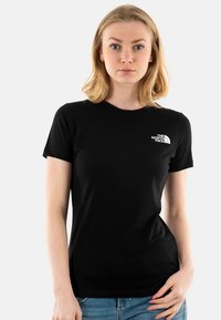 Mustast puuvillast valmistatud lühikeste varrukatega t-särk, millel on vasakul rinnal väike valge logo, ümar kaelus ja kitsas lõige.