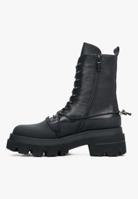 Zwarte leren combatboot met een stevige platformzool, vetersluiting aan de voorkant, zijrits en decoratieve koorddetails. Matte en gladde texturen.