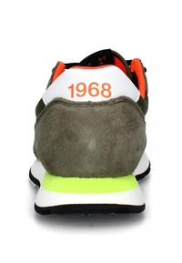 Scarpa da ginnastica verde in suede con accenti bianchi e giallo neon. Presenta il testo arancione "1968" sul tallone e una fodera in rete.