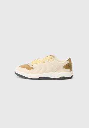 Beige og kremfarget sneaker med semsket skinn og syntetiske materialer, med bølgedesign, gule lisser og svart såle. Merkbar logoaccent.