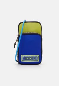 Borsa a due scomparti blu e verde con chiusura a zip, dotata di un'etichetta logo Moschino e di una tracolla blu. Realizzata in materiale liscio.