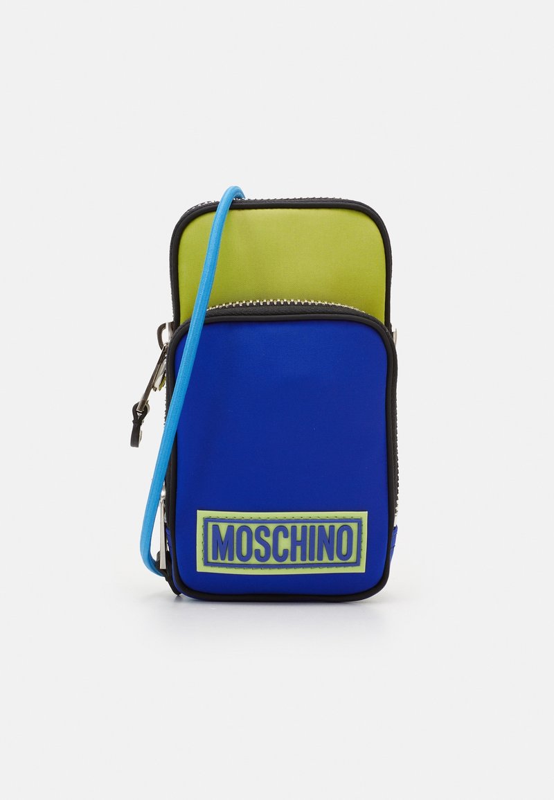 Blå och grön tvåfacksväska med dragkedja, utrustad med en Moschino-logopatch och en blå axelrem. Tillverkad av ett mjukt material.