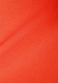 Jasnopomarańczowy materiał z teksturowanym wzorem plecionki; lekki i gładki, odpowiedni do odzieży lub tapicerki.