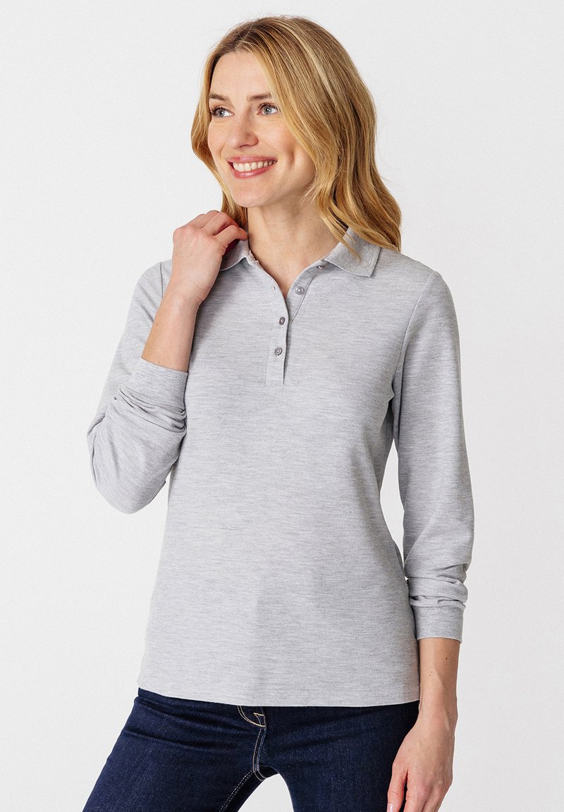 Lichtgrijze longsleeve polo met een kraag en een drieknoopsluiting, gladde textuur, gecombineerd met donkerblauwe jeans.