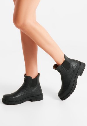 Black rubber ankle boots with a crocodile texture, elastic side panels, and a chunky sole, showcasing a sturdy design and waterproof material.
