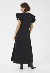Črna maksi obleka z nabranimi kratkimi rokavi, zadrgo na hrbtni strani in gladko teksturo materiala. Ustvarjeno z gležnjarji.