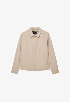Beige letvægtsjakke med lynlås foran, spids krave og to sidelommer. Har et minimalistisk logo på venstre side. Glat tekstur.