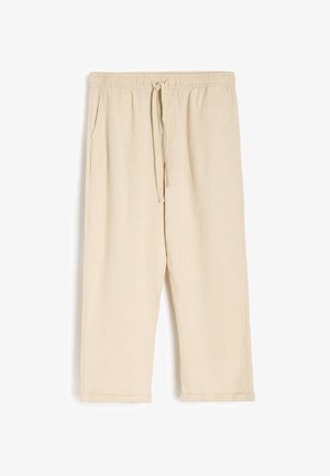 Beżowe lniane spodnie dresowe z elastycznym pasem i sznurkiem. Posiadają boczne kieszenie oraz podwinięte mankiety przy kostkach.