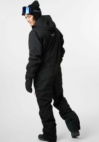 Zwarte sneeuwbroek met capuchon, ritssluitingen en elastische polsmanchetten. Voorzien van een logo op de achterkant en een strakke pasvorm voor wintersporten.