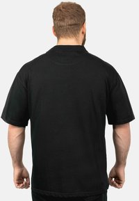 Zwarte t-shirt met korte mouwen, ronde hals en een relaxed fit. De stof lijkt geribbeld en heeft geen zichtbare logo's of patronen.