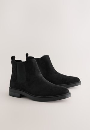 Mustat mokkanahkaiset nilkkurit, joissa on joustavat sivupaneelit, vetoluukut ja tasaiset kumipohjat. Sileä pinta ja tyylikäs, minimalistinen muotoilu.