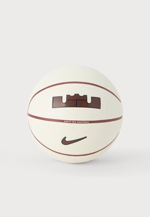 Witte basketbal met bruine naden, Nike swoosh-logo en de tekst "Strive for Greatness" onder een kroonvormig embleem.