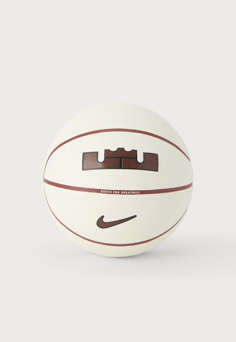 Λευκή μπάλα μπάσκετ με καφέ ραφές, λογότυπο Nike swoosh και κείμενο "Strive for Greatness" κάτω από ένα έμβλημα με σχήμα κορώνας.