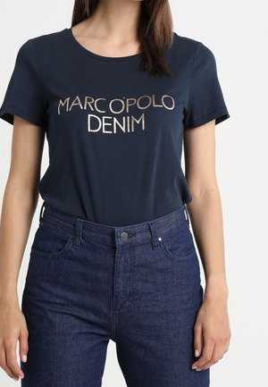 Marineblå t-shirt med korte ærmer, prydet med metallisk tekst "MARCO POLO DENIM". Sammen med mørkeblå denim jeans med klassisk pasform.
