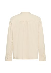 Garām piedurknēm bēšs krekls ar apkakli, aizmugurējo daļu ar plecu daļu un pogām aizdarāmām aprocēm, attēlots no aizmugures uz baltas fona.