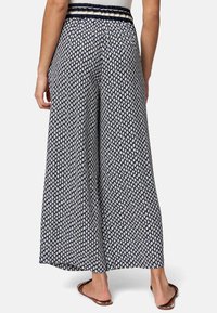 Weite Hosen in Marineblau mit einem geometrischen Muster in Creme, ausgestattet mit einem elastischen Bund und leichtem Stoff für hohen Tragekomfort.