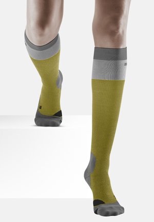 Calze fin sopra il ginocchio con un corpo giallo e dettagli grigi e neri. Tessuto testurizzato con zone imbottite per supporto e punta rinforzata.