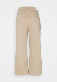 Beiga vida byxor med hög midja, femfickorsdesign och kontrasterande sömmar. Tyget har en jämn textur. Bakifrån synlig.