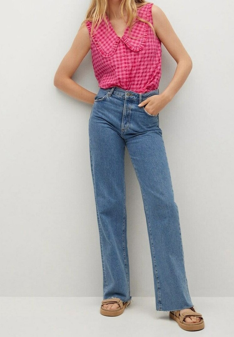 Blouse sans manches à carreaux roses avec un col Claudine, associée à un jean bleu clair taille haute à jambes droites et des sandales couleur sable.