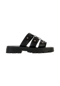 Sandale plate noire avec semelle épaisse et trois larges brides fixées par des rivets dorés, conçue pour un usage décontracté.