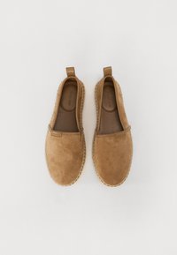 Barna velúr slip-on cipők lekerekített formával, varrással a talpnál és egy kis húzófüllel a saroknál. Lapos, texturált bélés.