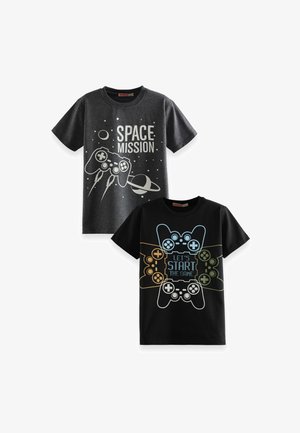 Deux t-shirts : l'un gris avec le texte blanc "MISSION SPATIALE" accompagné d'une manette et de planètes ; l'autre noir avec des manettes colorées et le texte "COMMENÇONS LE JEU."