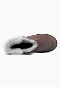 Zapatilla de ante marrón con un suave collar y interior de piel sintética gris, con punta redonda y suela plana. Diseño simple y acogedor.