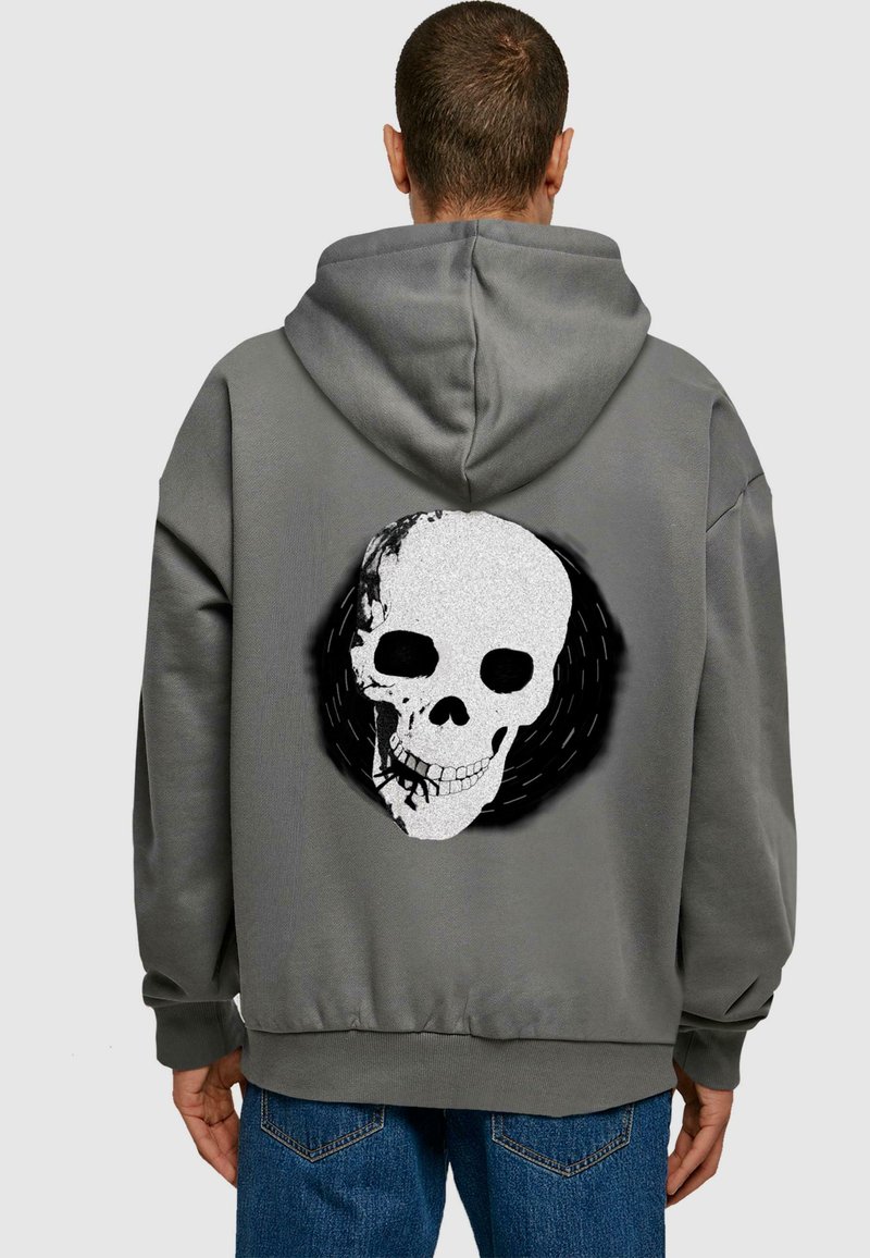 Felpa grigia con cappuccio, caratterizzata da una grande grafica di teschio bianco e nero sul retro, con vestibilità rilassata e polsini a coste.