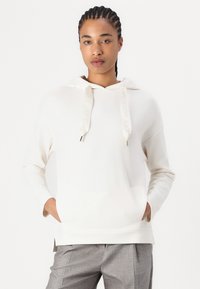 Cremefarbener Kapuzenpullover mit Kordelzug, der Logoschmuck aufweist, lockere Passform und Kängurutasche. Lange Ärmel und seitliche Schlitze am Saum.