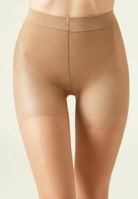 Shorts gainants beiges avec un design sans couture et un motif texturé. Fabriqués à partir d'un tissu lisse et extensible, avec une large taille élastique.