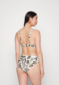 Conjunto de biquíni floral com alças ajustáveis, costas baixas, com uma base branca, padrão de folhas de palmeira verdes e roxas, e parte de baixo de cintura alta.