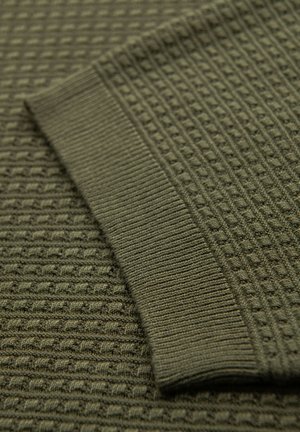 Tessuto di maglia verde textured con un polsino a coste. Presenta un motivo a griglia che crea profondità e variazioni di interesse visivo.