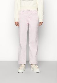 Jeans de ganga rosa claro com um design de perna reta, estilo de cinco bolsos e fecho de botão. Usados com um moletom de cor creme e ténis brancos.