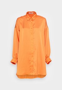 Camisa naranja de manga larga fabricada con tejido suave. Presenta un cierre frontal de botones, cuello clásico y un leve fruncido en los puños de las mangas.