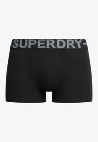 Schwarze Boxershorts aus Baumwollmischung mit einem grauen elastischen Bund, auf dem "SUPERDRY" in fetter, sportlicher Schrift gedruckt ist.