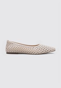 Chaussure plate beige à bout pointu, fabriquée en matériau perforé avec un motif en grille et une semelle basse texturée.