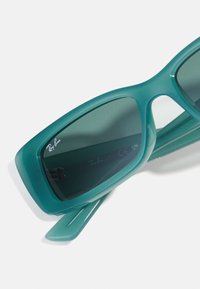 Ochelari de soare Ray-Ban de culoare turquoise, cu un cadru robust, lentile închise la culoare și detalii cu logo pe braț, având o finisare netedă și lucioasă.