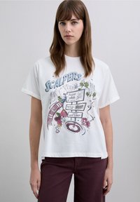 White cotton t-shirt with short sleeves, featuring colorful graphic print of casino elements and the word "SCALPERS." Round neckline.